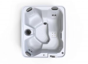 Top-down view of a white rectangular hot tub with multiple molded seats, built-in jets, and a control panel on the edge.