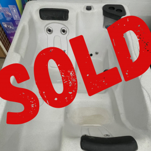 Showroom white hot tub interior with jets, covered by a large red SOLD stamp indicating it’s sold.