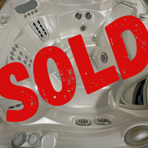 White hot tub interior with multiple jets and seating, overlaid by a large red 'SOLD' stamp indicating it’s sold.