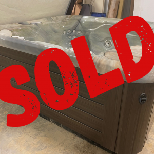 Hot tub with multiple jets and a light wood exterior, indoors, covered with a large red SOLD watermark across the image.