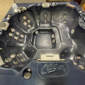 Blue-gray hot tub interior with numerous water jets and built-in seating, showing cushioned headrests and a textured non-slip floor surface.