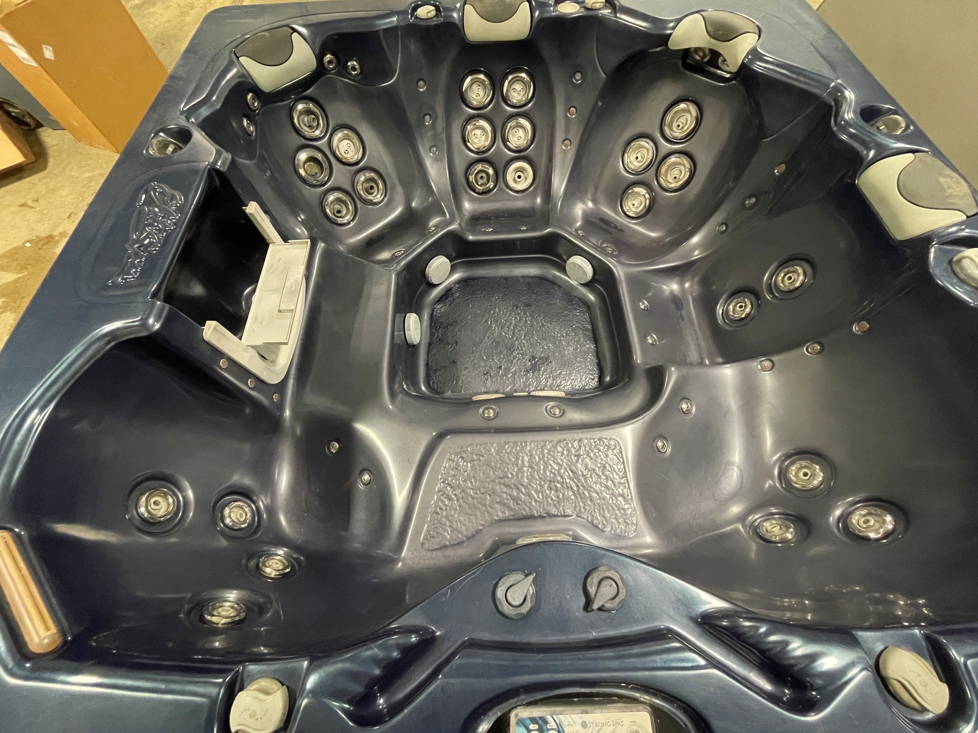 r397 4 | Young's Hot Tub Sales and Service Center Dark blue hot tub interior with multiple silver massage jets and light-colored headrests along the edges.