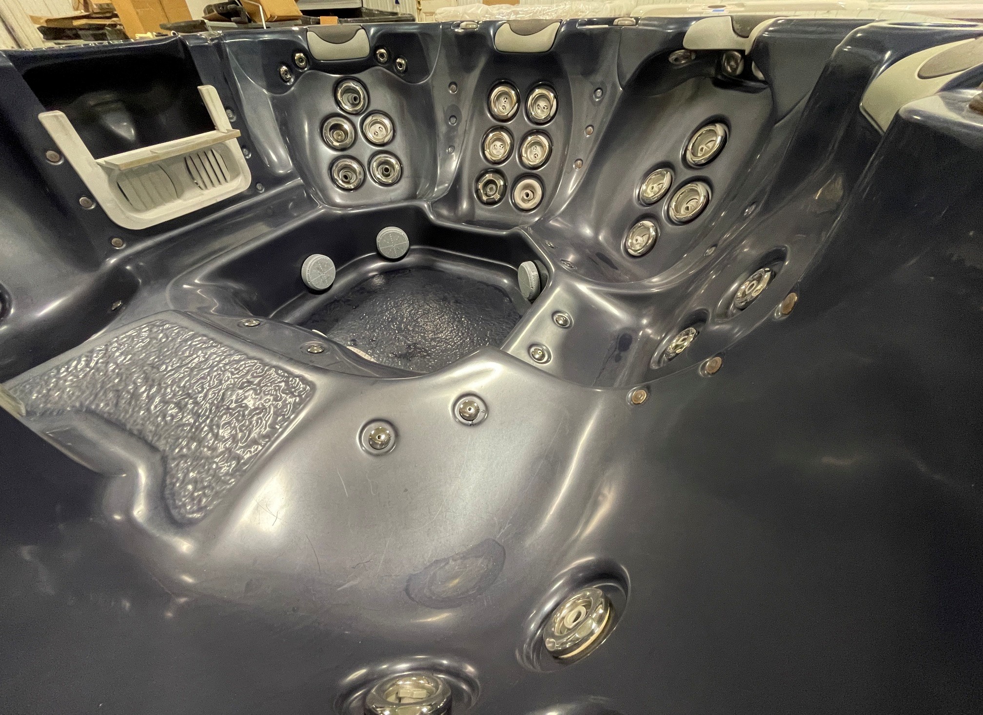 r397 6 | Young's Hot Tub Sales and Service Center Interior of a dark gray hot tub with numerous circular jets built into the molded walls, and small seating areas visible behind them.