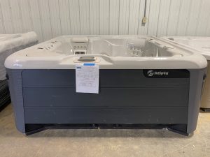 r408 1 | Young's Hot Tub Sales and Service Center White HotSpring hot tub in a showroom with protective plastic cover and a spec sheet taped to the front panel