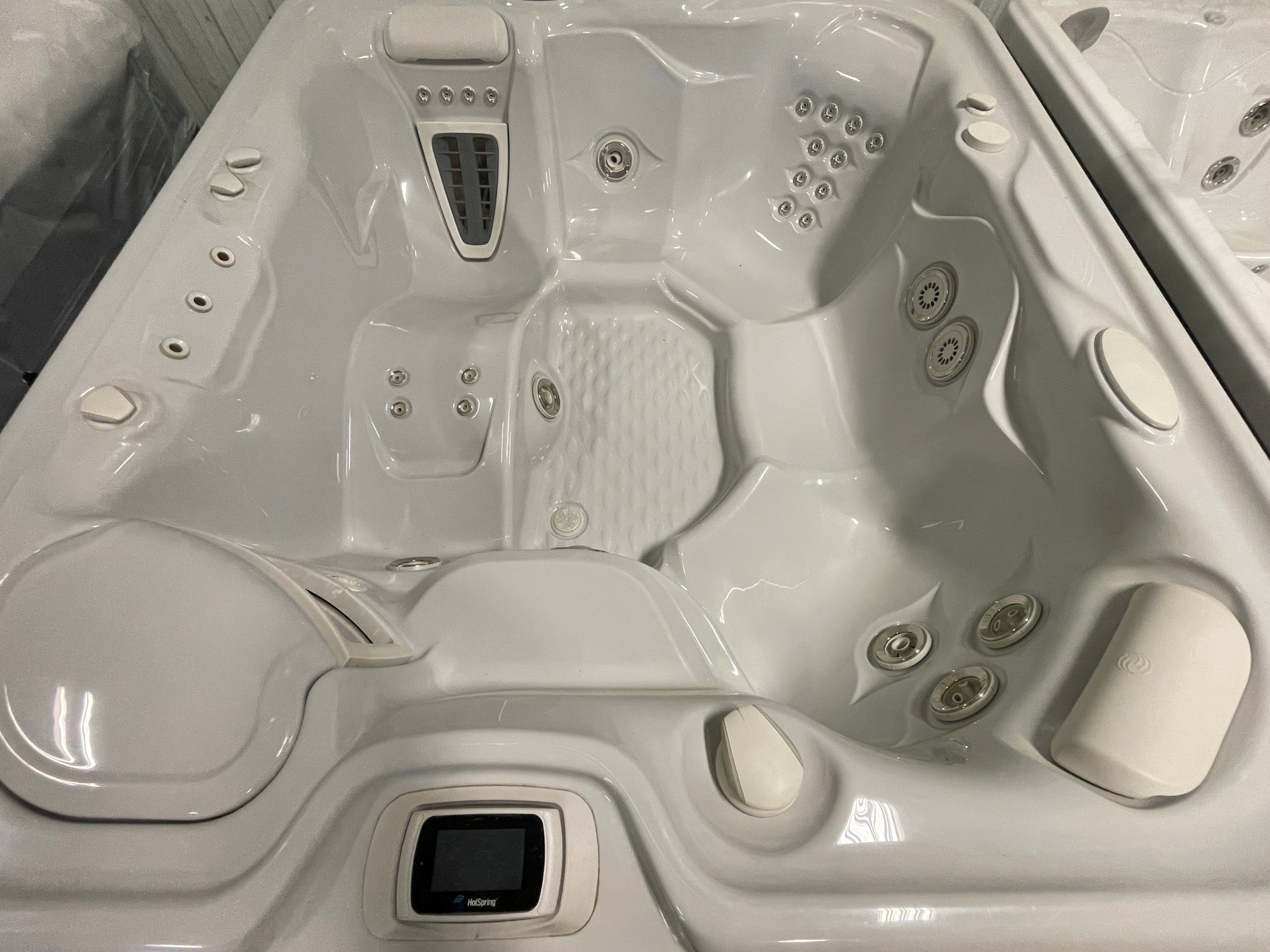 r408 2 | Young's Hot Tub Sales and Service Center A white spa hot tub interior with multiple jet clusters, built-in seats, and a central control panel labeled HotSpring at the bottom.