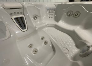 r408 5 | Young's Hot Tub Sales and Service Center White hot tub interior with multiple jet nozzles, built-in seat, and control panel on the left.