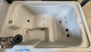 r442 2 | Young's Hot Tub Sales and Service Center Interior of a gray speckled hot tub with multiple stainless jets and raised seating contours, viewed from above.