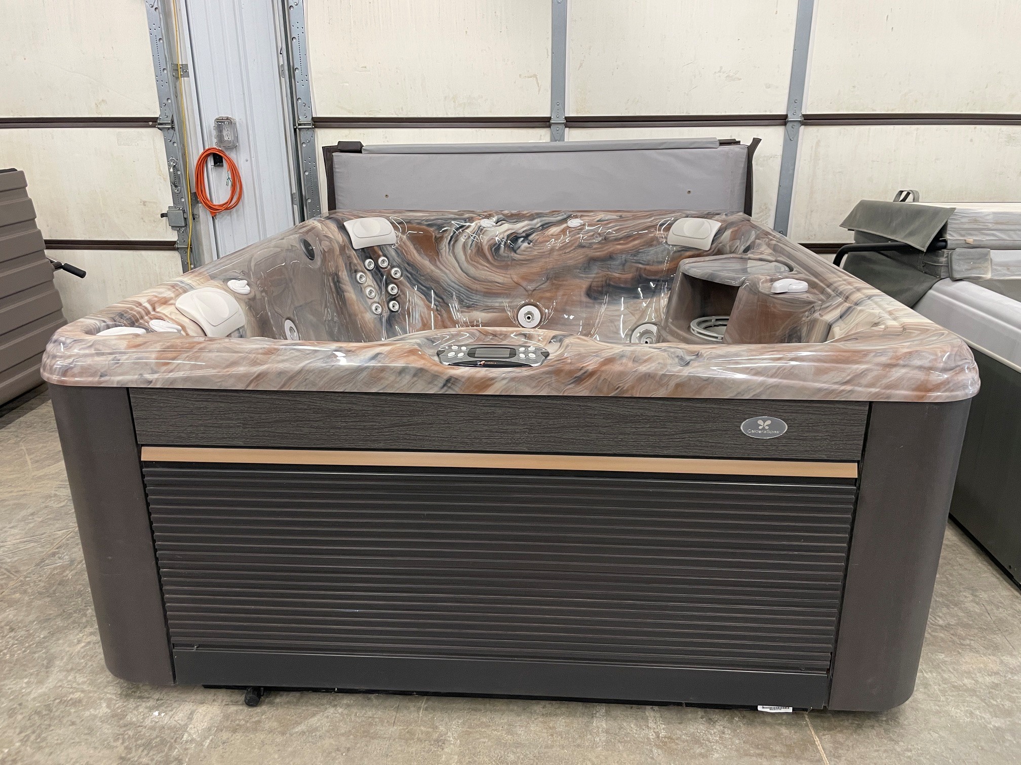 r441 1 | Young's Hot Tub Sales and Service Center Marbled hot tub in a showroom with a gray protective cover partially folded on top and control panel at the front.