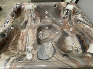 r441 5 | Young's Hot Tub Sales and Service Center Marbled acrylic hot tub with numerous jet nozzles, covered in protective plastic wrap for shipping or installation.
