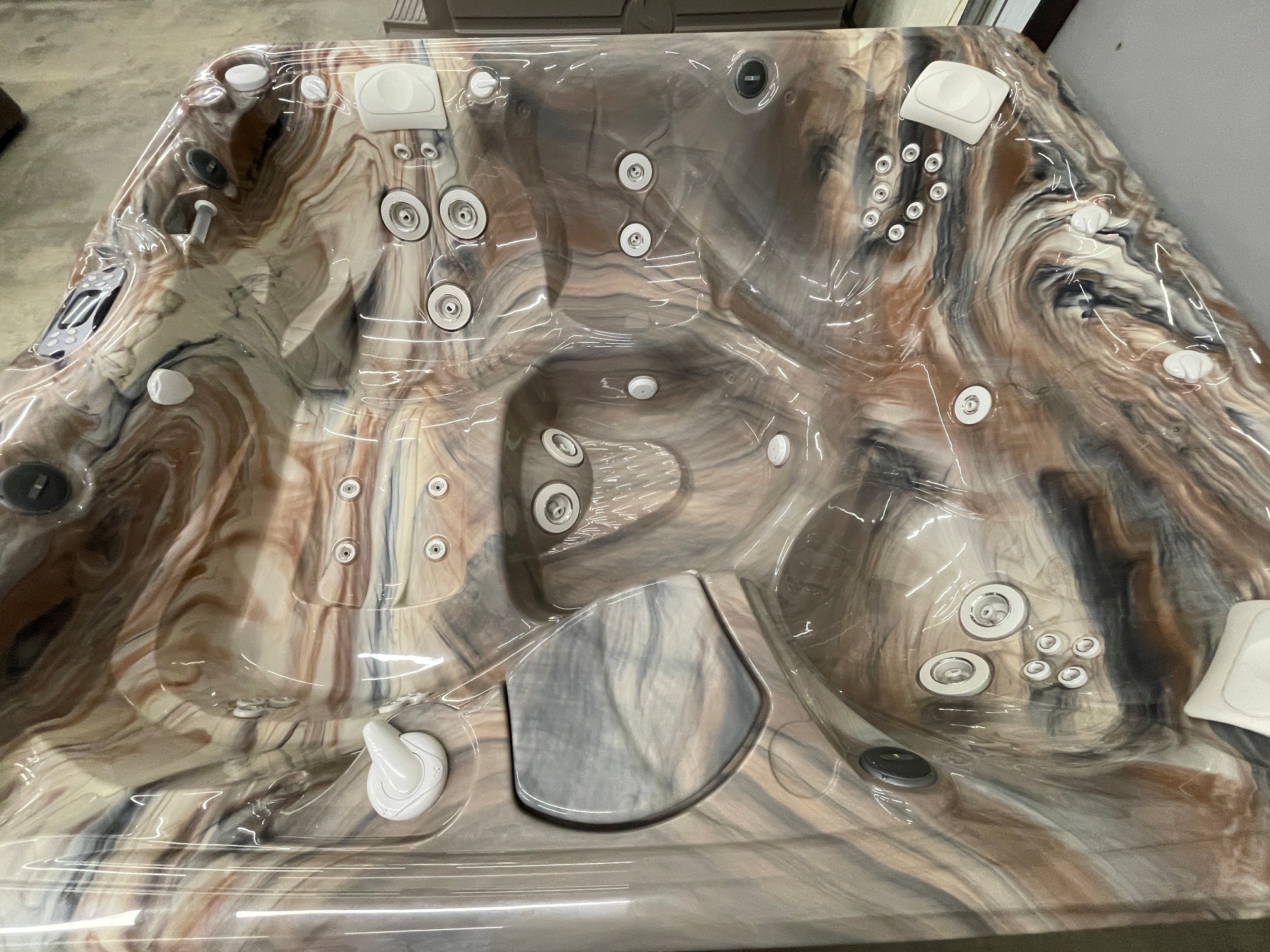 r441 5 | Young's Hot Tub Sales and Service Center Marbled acrylic hot tub with numerous jet nozzles, covered in protective plastic wrap for shipping or installation.