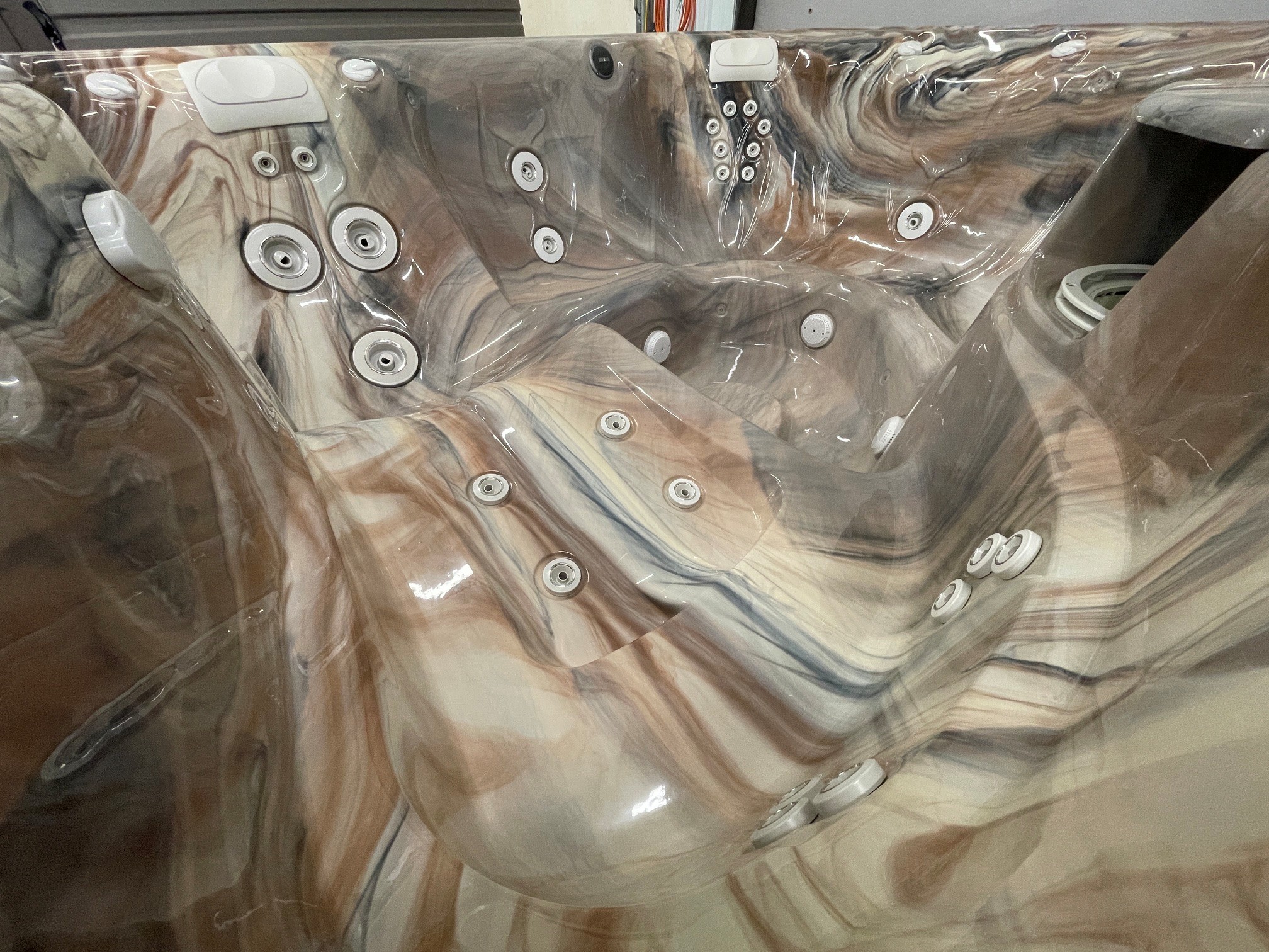 r441 6 | Young's Hot Tub Sales and Service Center Marble-patterned hot tub interior with many white jets and a built-in headrest, covered in plastic wrap.