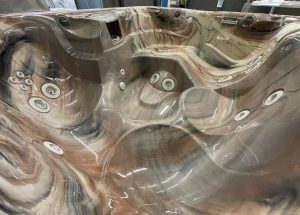 r441 7 | Young's Hot Tub Sales and Service Center Brown marbled hot tub interior with multiple circular jets and built-in seats, wrapped in plastic.