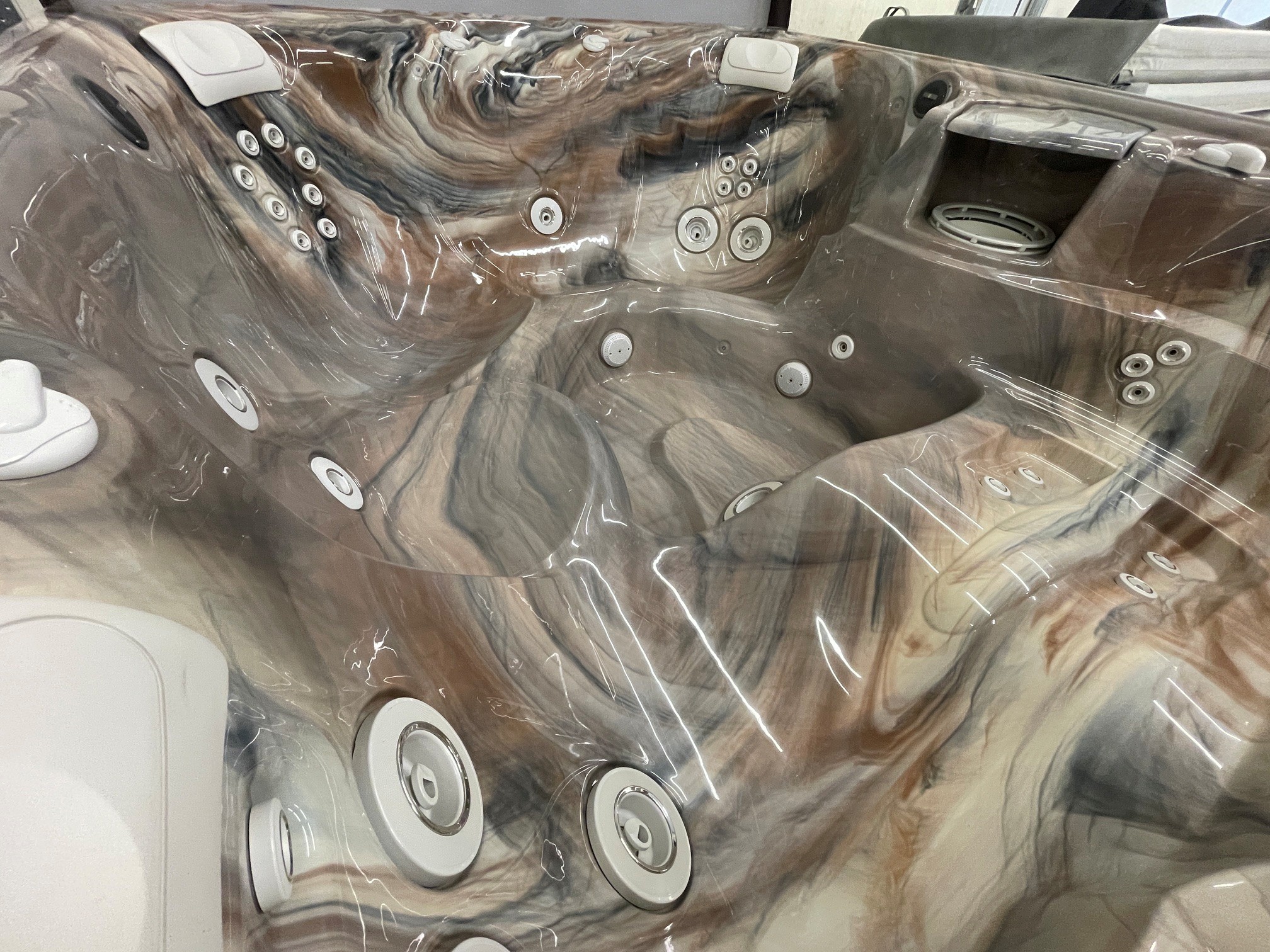 r441 8 | Young's Hot Tub Sales and Service Center Glossy brown hot tub interior with multiple circular jets and built-in seating, covered in protective plastic wrap.